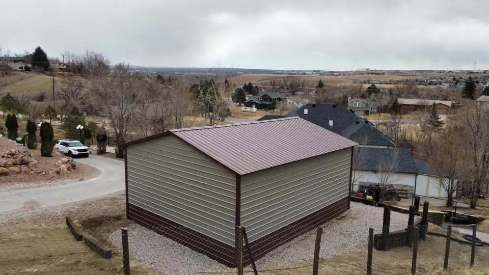 Side view of a tan 24x30 steel garage with brown trim and roof