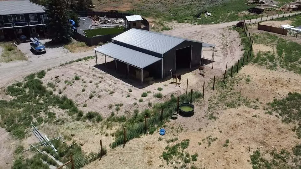 Aerial view of a steel AG building with full-length lean-tos beside a fenced pasture