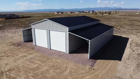 White steel building with two white roll-up doors and lean-tos on both sides on the plains