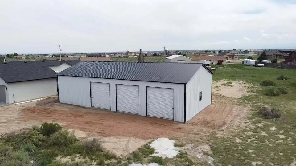 White 30x60 steel building with three roll-up doors and a black roof
