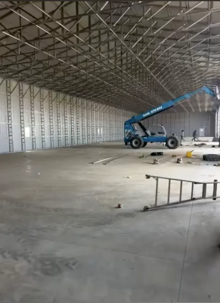 Interior of a 60x250 commercial steel building with a boom lift on the concrete floor
